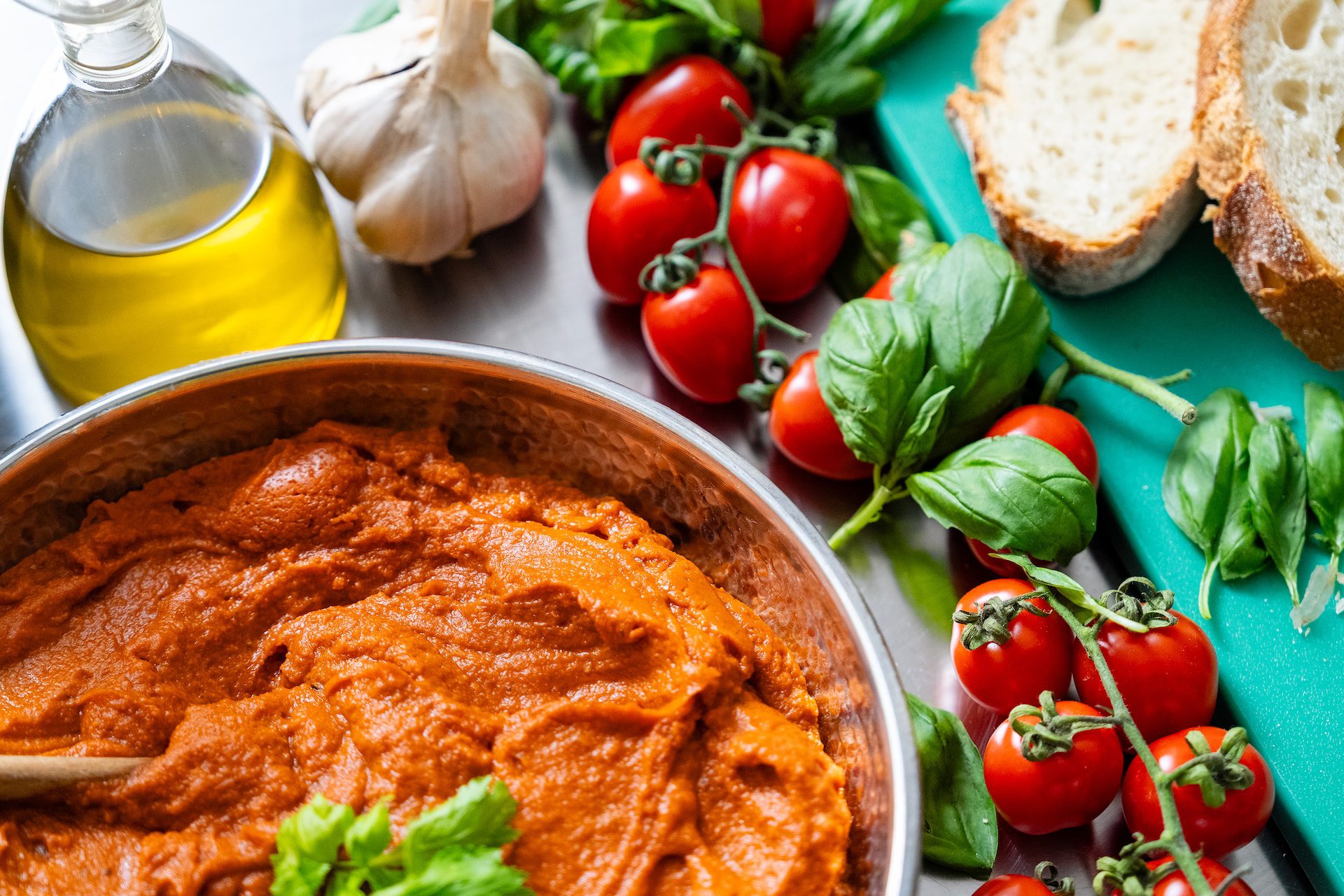Dettaglio di una pentola con pappa al pomodoro e a fianco ingredienti come pomodori, basilico e olio